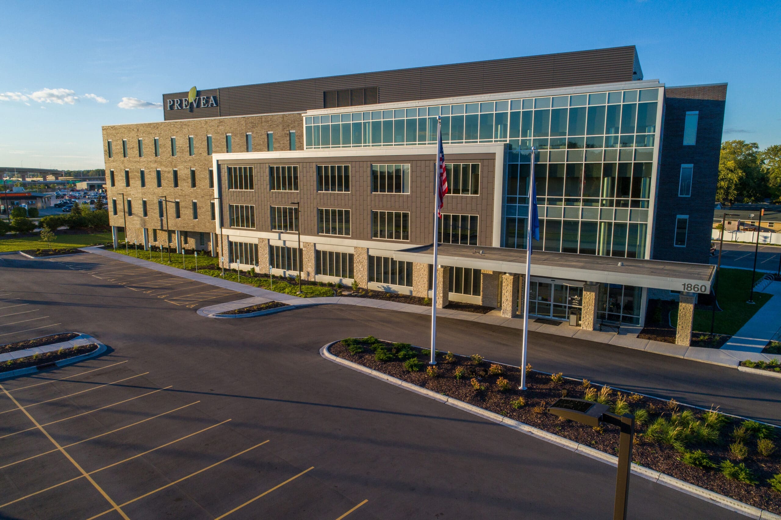 Commercial real estate photo of a four-story medical office building with glass and brick facade, Prevea sign, and empty parking lot.
