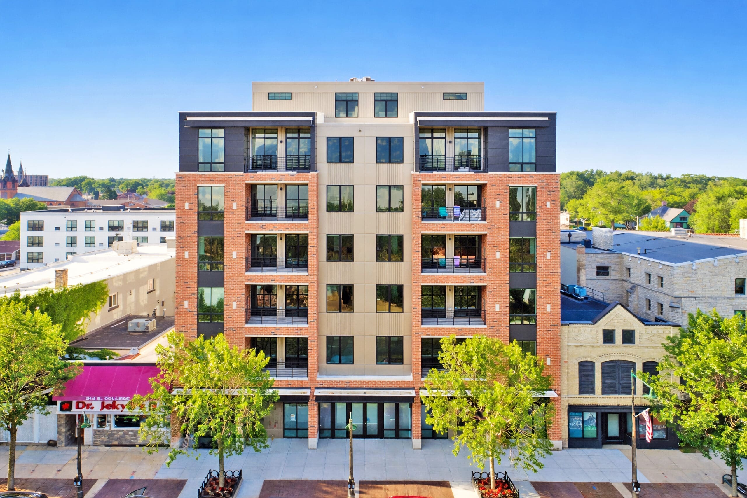 Contemporary six-story residential apartment building with retail storefronts, balconies, and brick façade—ideal for real estate listings.