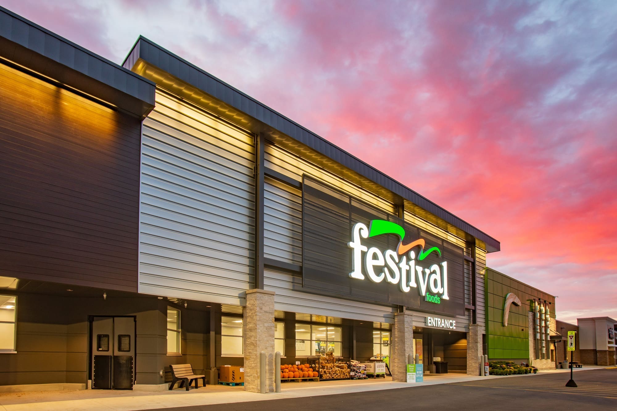 Commercial real estate photo of Festival Foods grocery store exterior at sunset, entrance and signage showcased under vibrant sky.