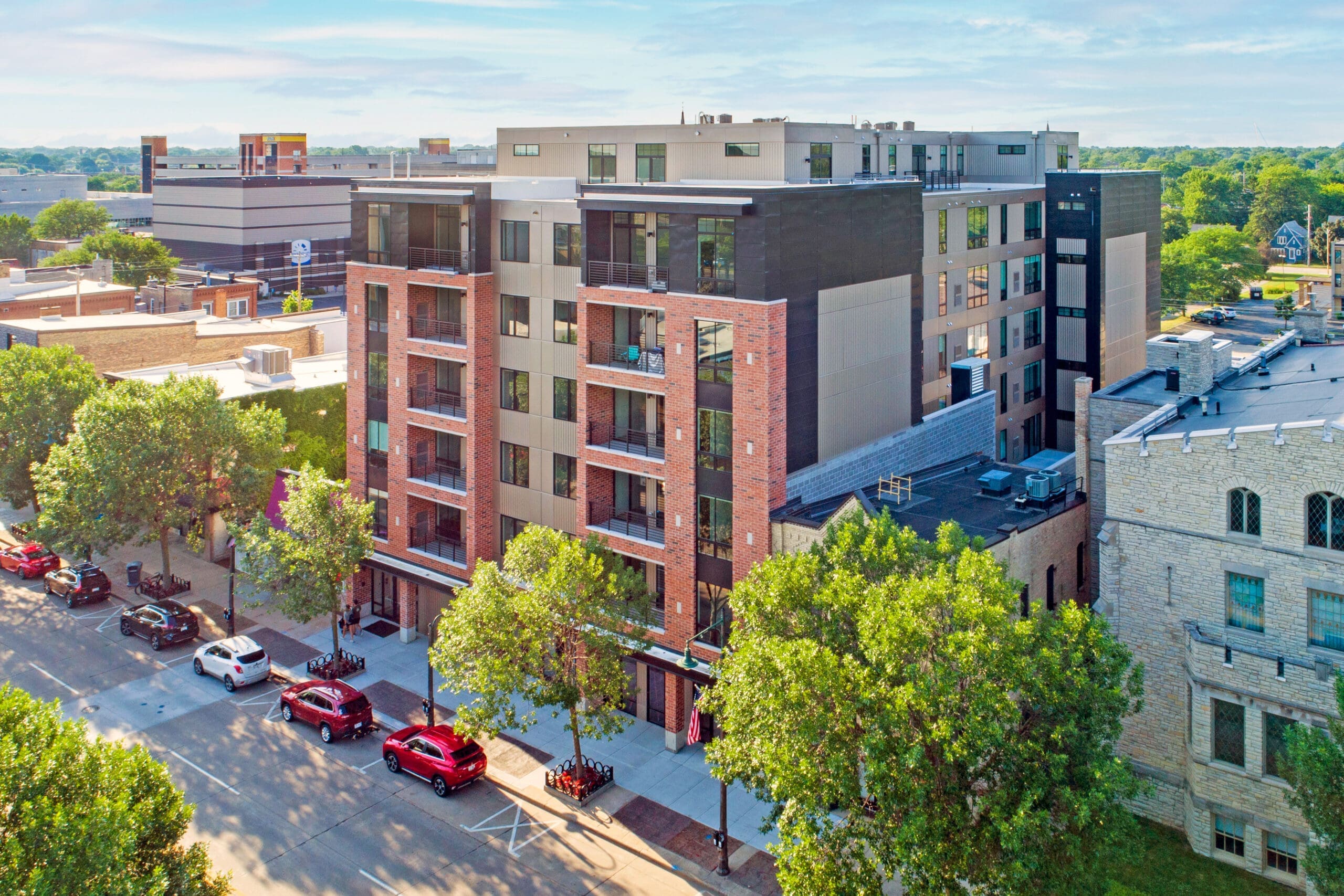 Contemporary mid-rise residential apartment building with balconies, large windows, brick facade; ideal real estate listing photo.