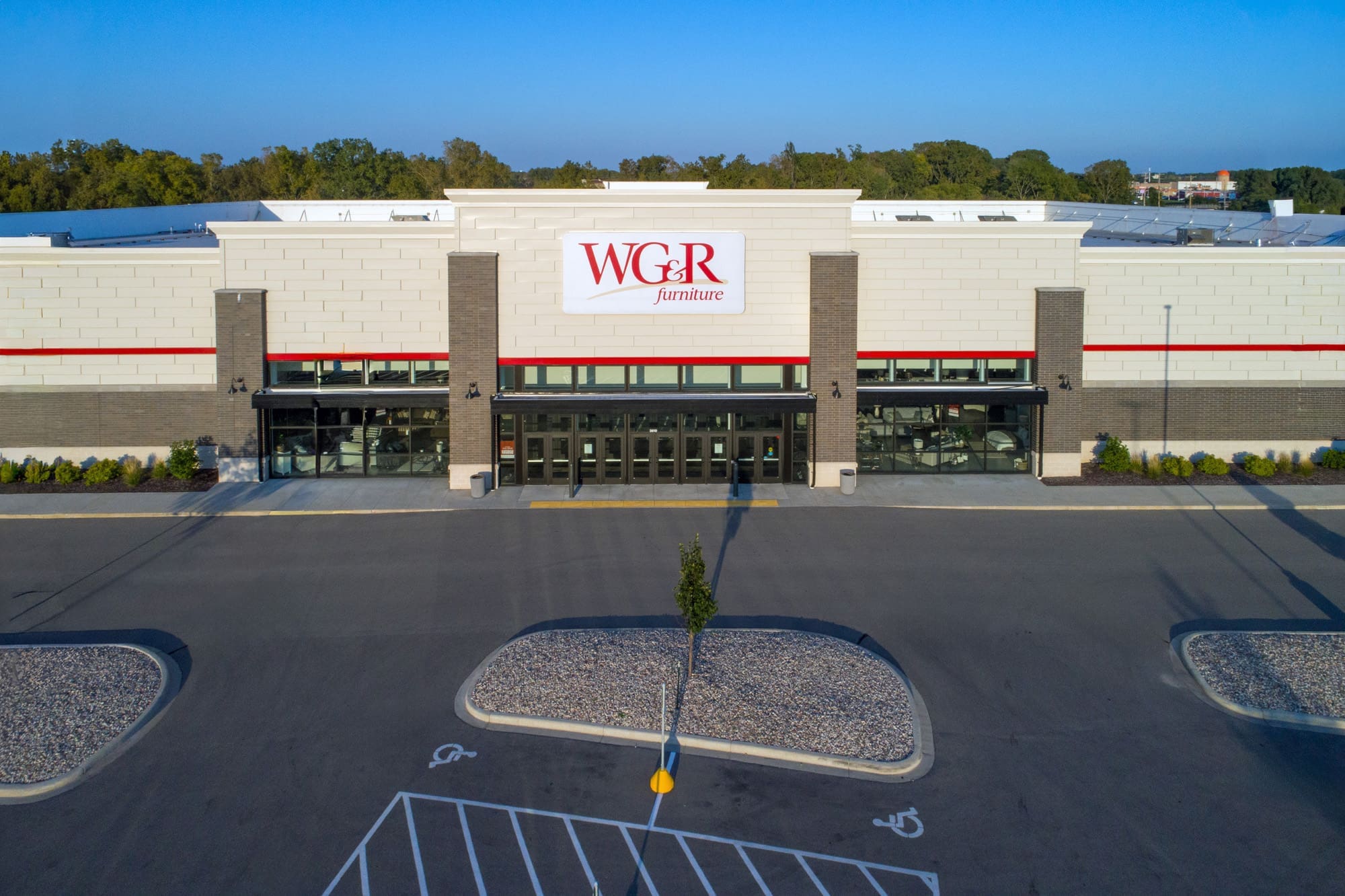 Commercial property exterior of WGR Furniture store featuring glass doors, wide entrance, empty parking lot, and clear blue sky.