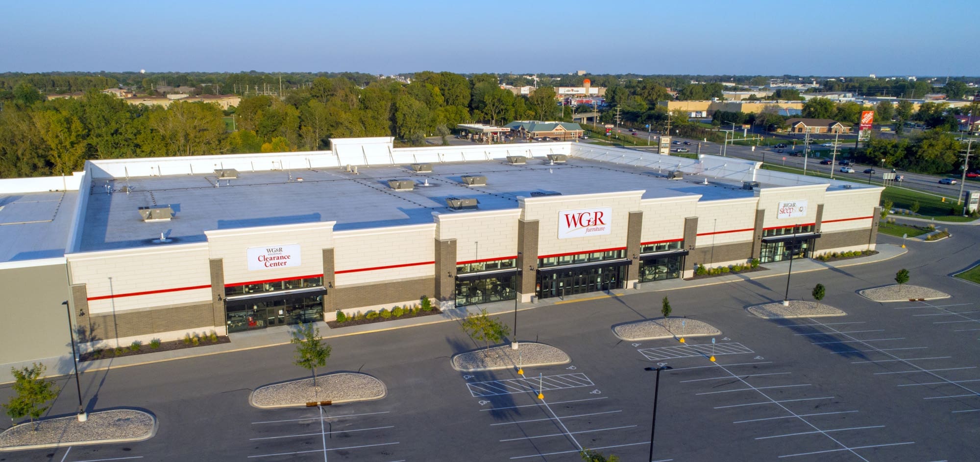 Commercial property featuring a large retail building marked “WGR Clearance Center,” ample parking, and trees in the background.