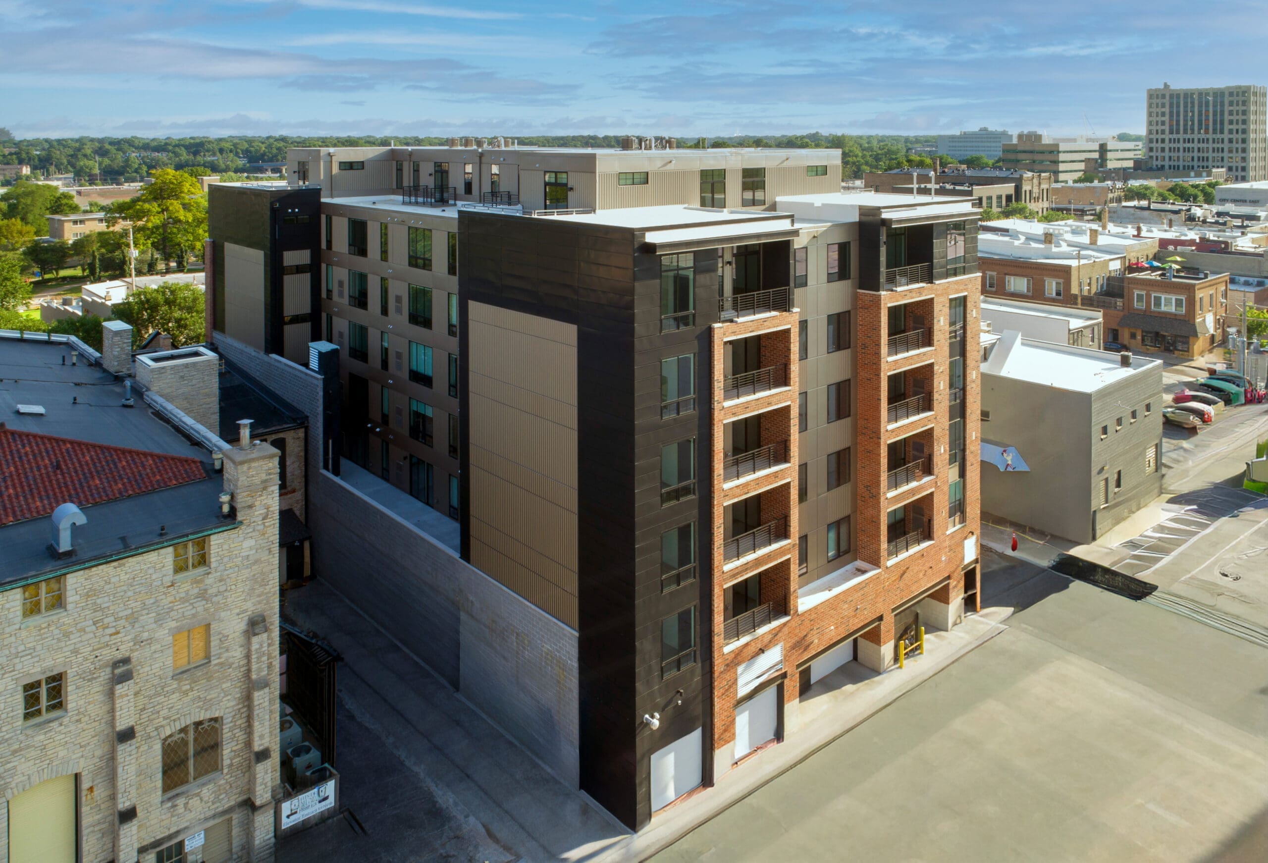 Modern mid-rise apartment building with balconies in urban setting, ideal for residential or commercial real estate photography.