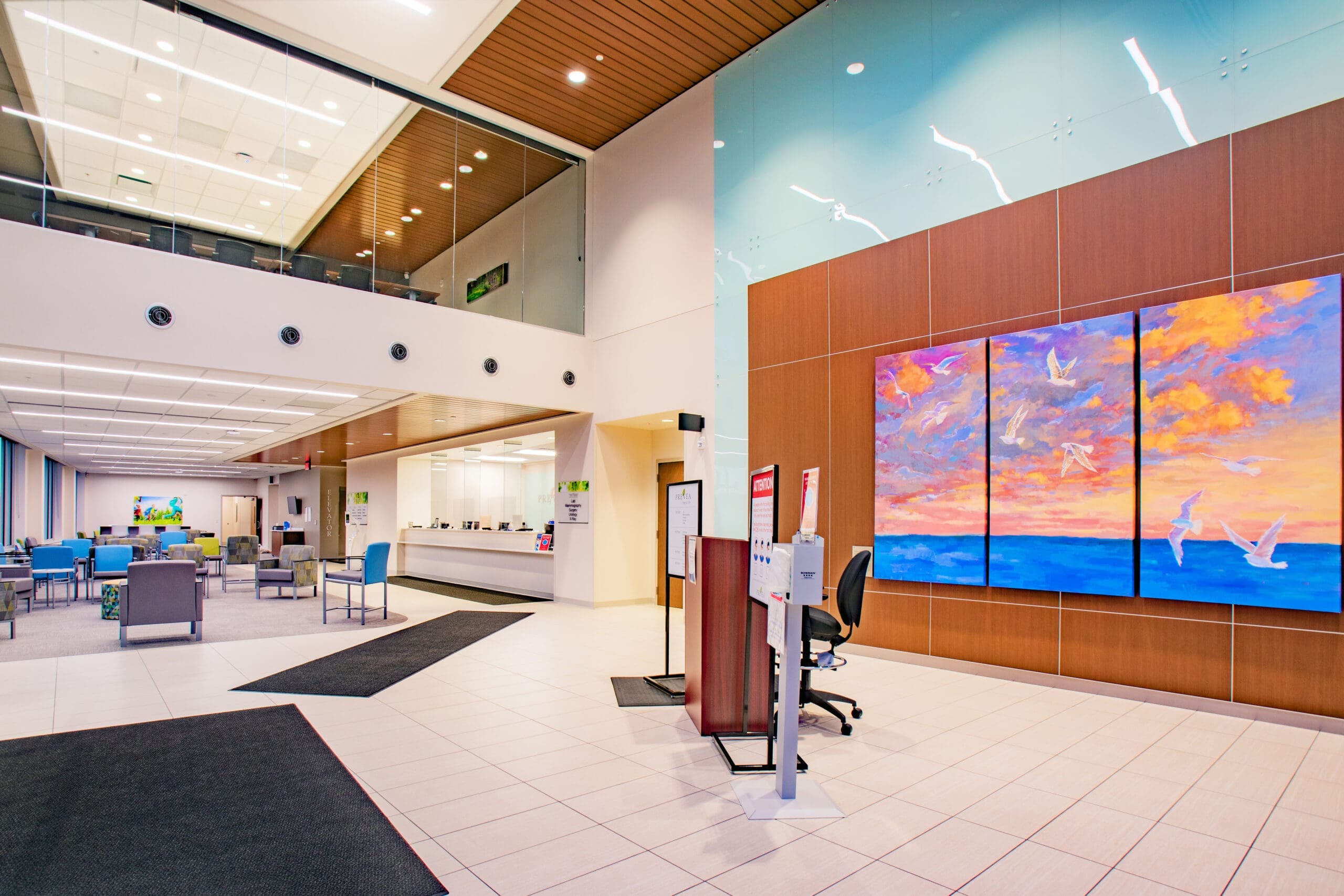 Commercial property lobby featuring modern design, bright lighting, seating area, vibrant wall art, and reception desk in view.