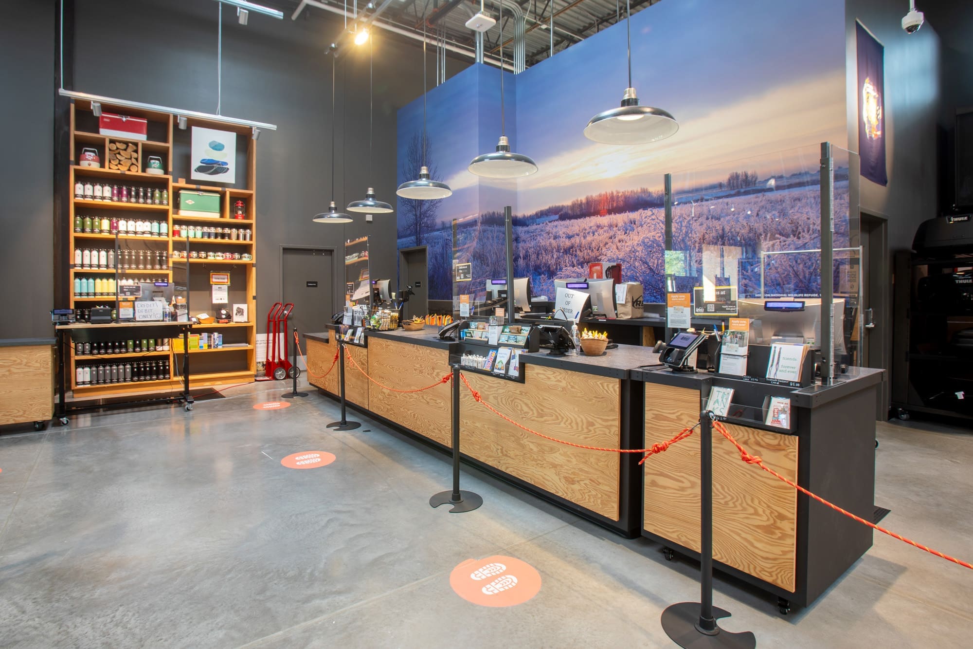Commercial coffee shop interior featuring a modern counter, plexiglass dividers, mural, and product shelves—ideal retail property.