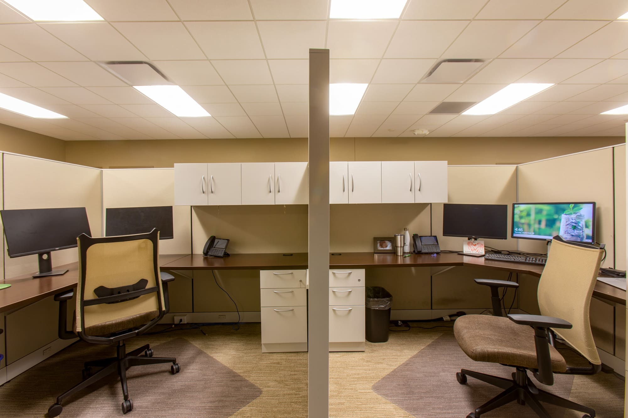 Modern commercial office space featuring two workstations, ergonomic chairs, storage, and ample lighting—ideal for business leasing.