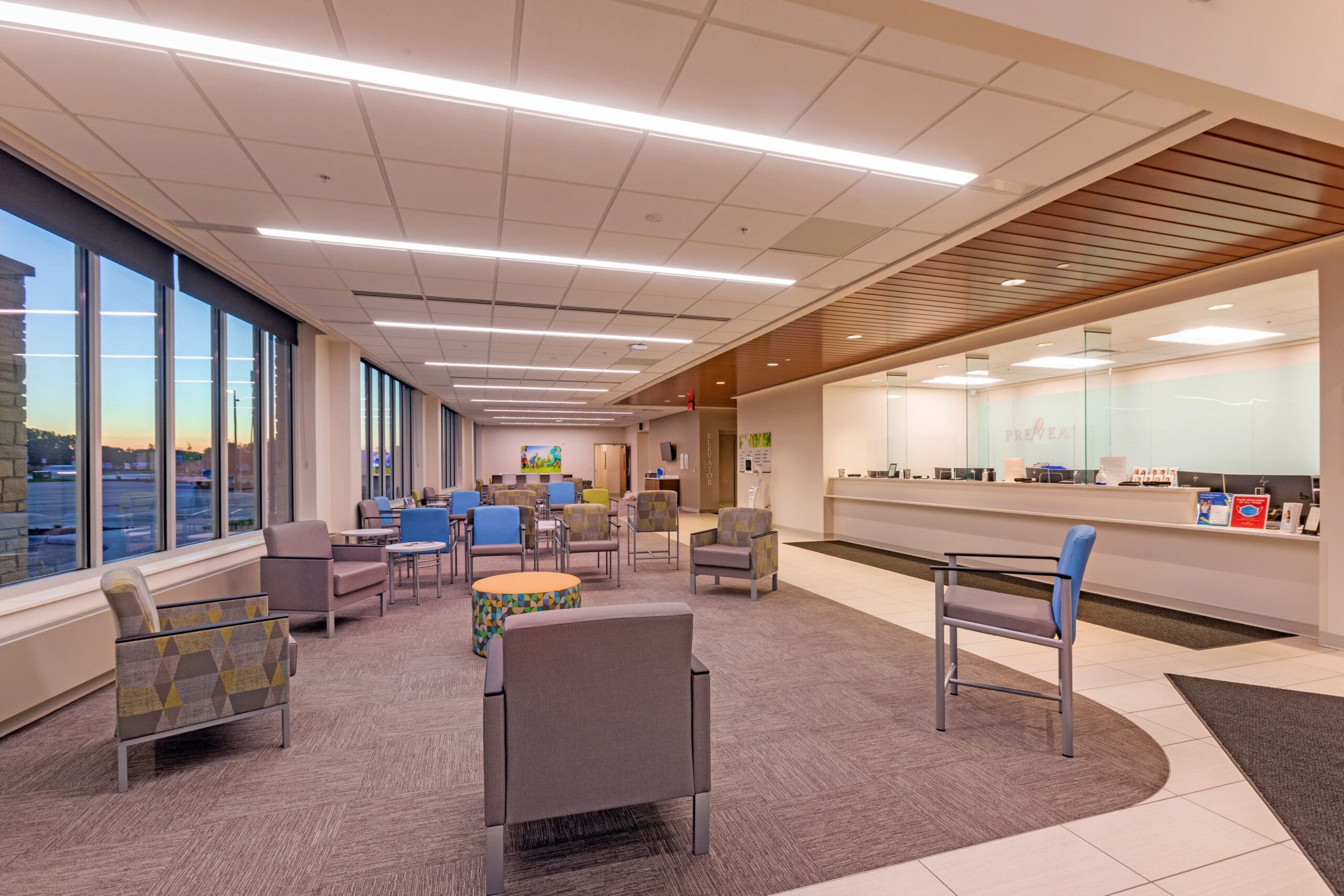 Modern commercial property waiting area featuring spacious seating, natural light from large windows, and a sleek reception desk.
