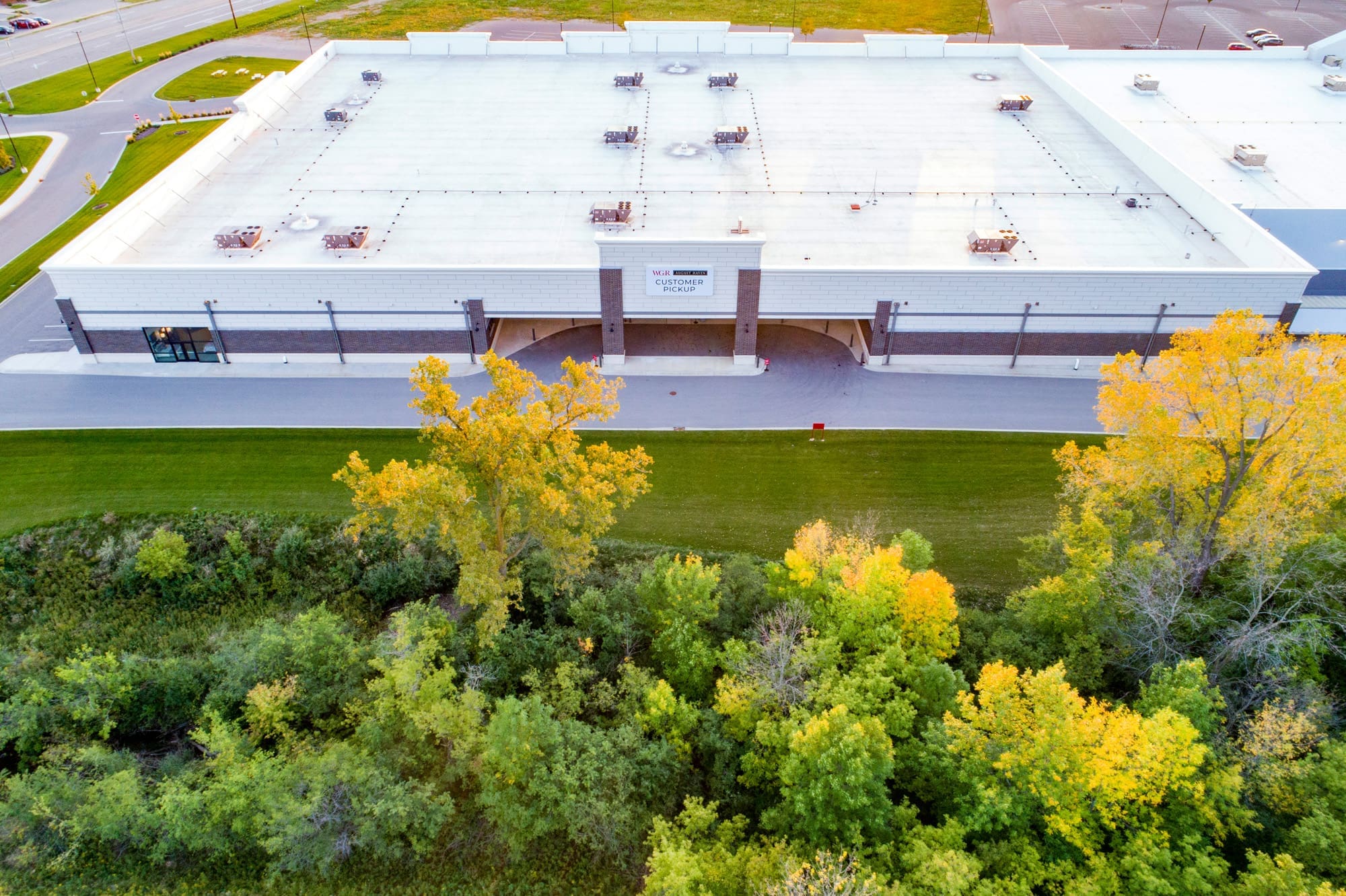 Aerial real estate photo of a white-roofed commercial property, landscaped grounds, and ample parking lot—ideal for business use.