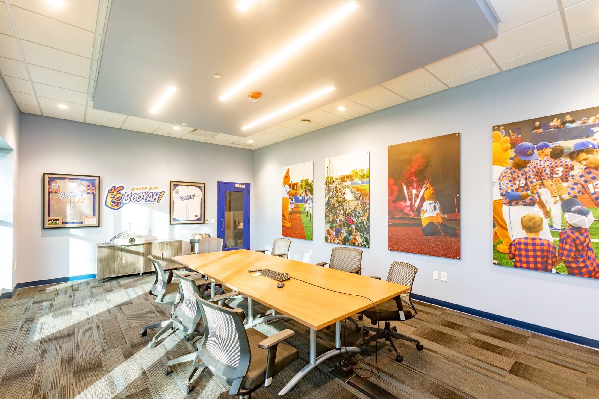 Commercial property conference room featuring a wooden table, office chairs, and sports-themed wall decor for business meetings.
