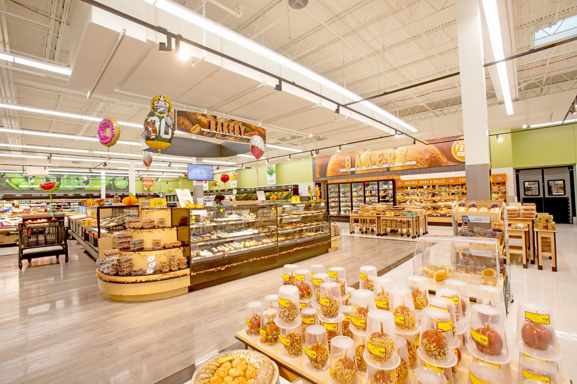 Bright commercial retail space showcasing a bakery section with assorted breads, pastries, cakes, and snacks under modern lighting.