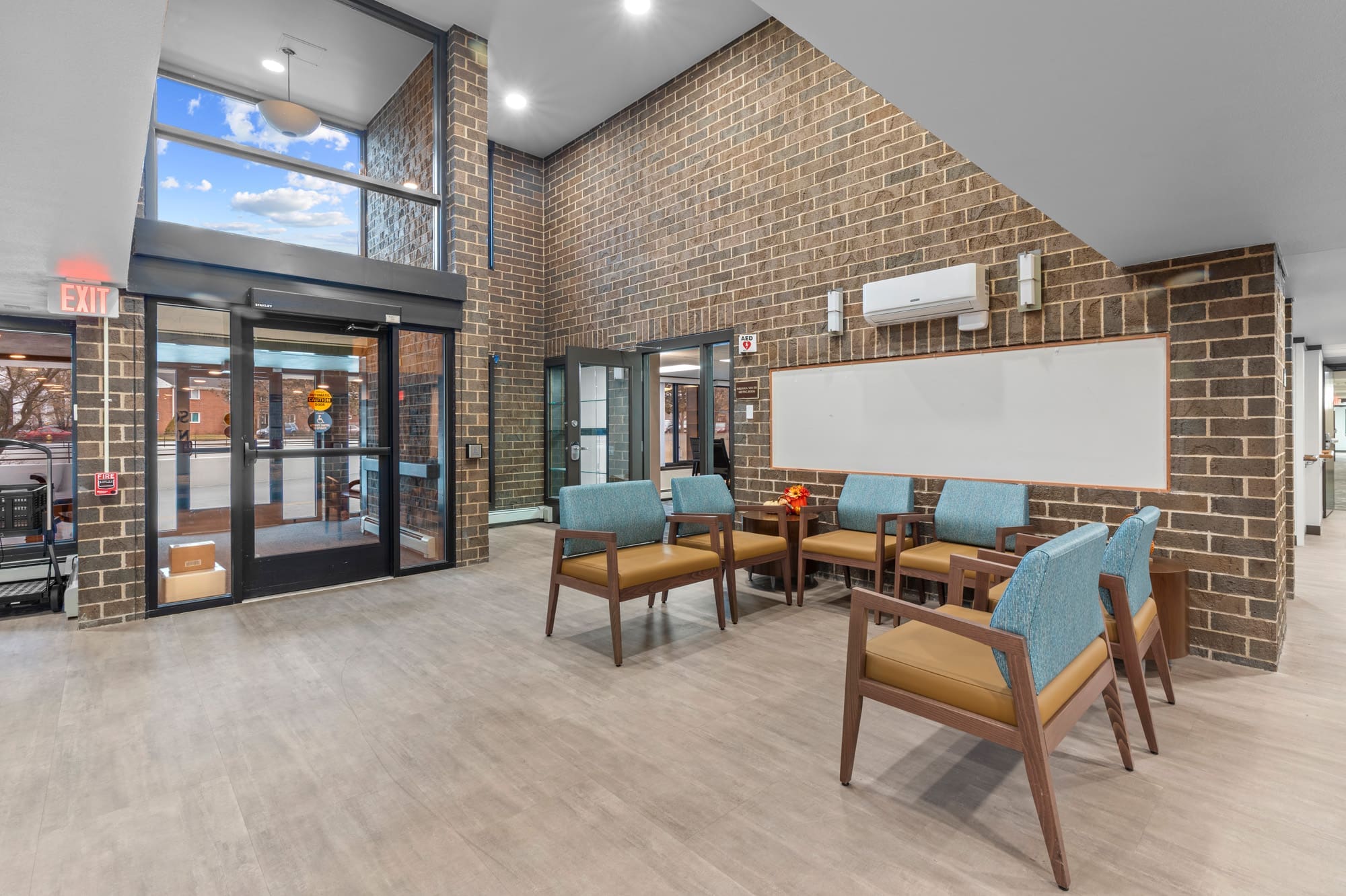 Commercial property lobby featuring exposed brick walls, blue seating, large windows, natural light, and contemporary fixtures.