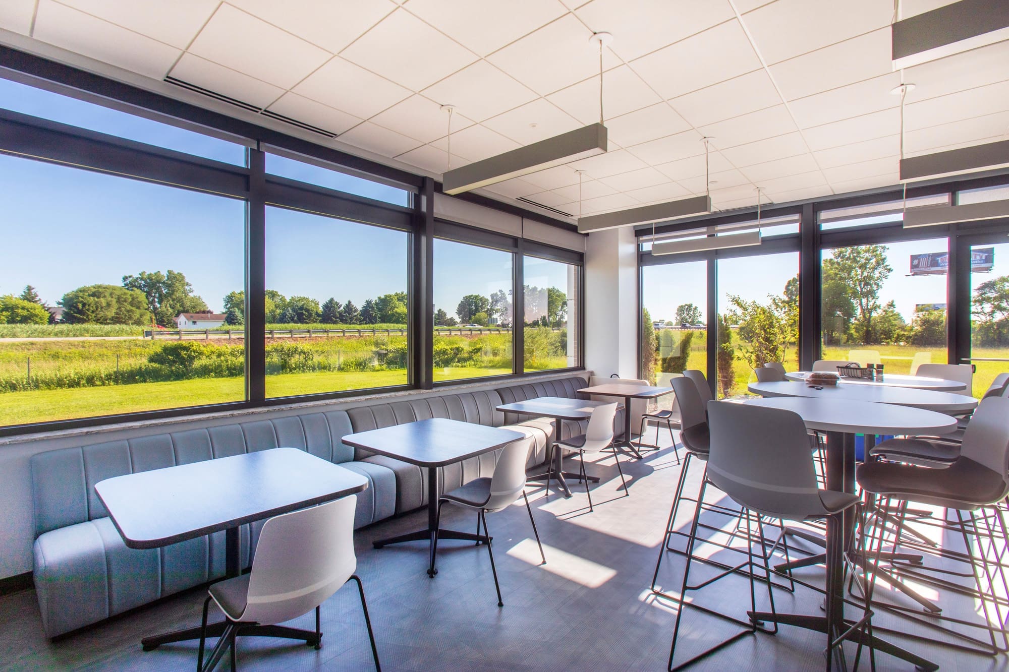 Spacious commercial cafeteria with modern tables, large windows, and scenic views of green fields—ideal for real estate listings.