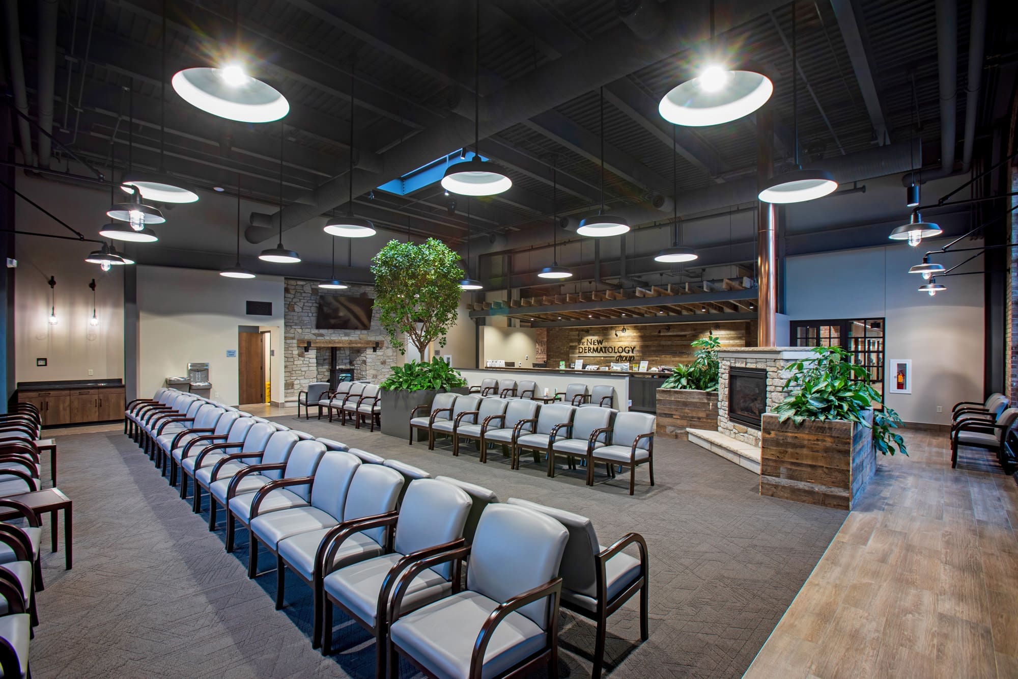 Spacious commercial lobby featuring cushioned seating, fireplace, indoor plants, and modern lighting—ideal real estate listing photo.