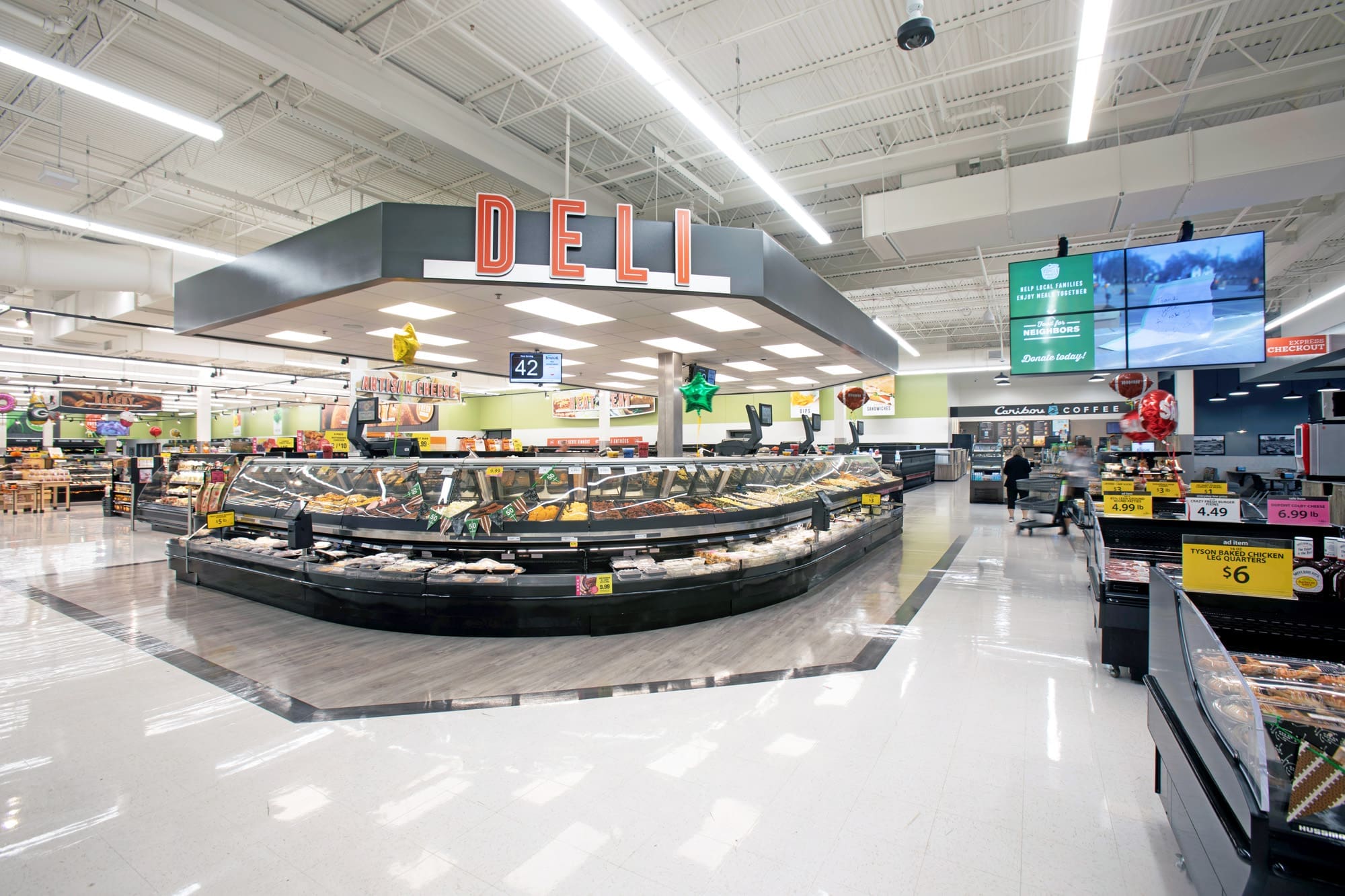 Commercial property interior featuring a bright deli section with prepared foods in glass cases beneath a prominent DELI sign.