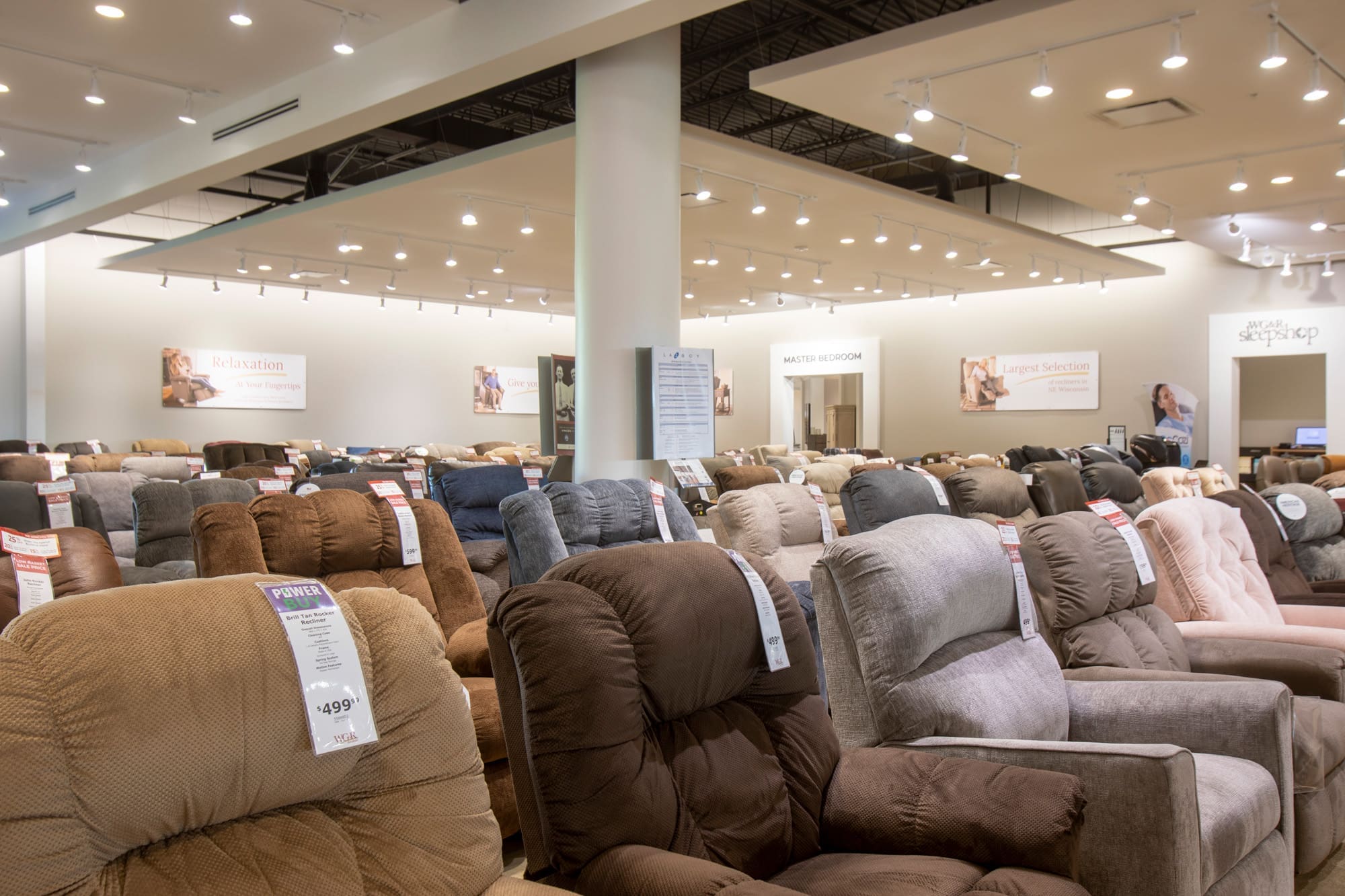 Commercial showroom interior featuring multiple recliner chairs in assorted colors, ideal for property staging, under bright lighting.