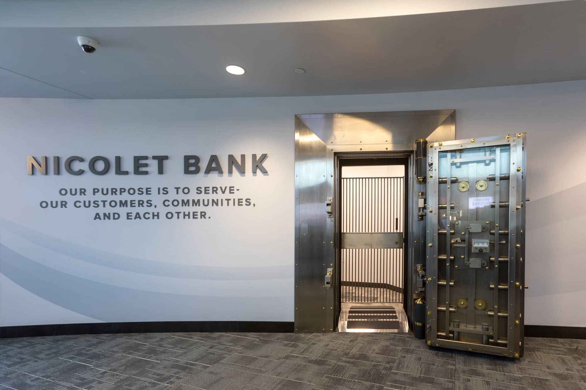 Commercial property interior featuring an open bank vault door and Nicolet Bank branding, ideal for real estate marketing photos.