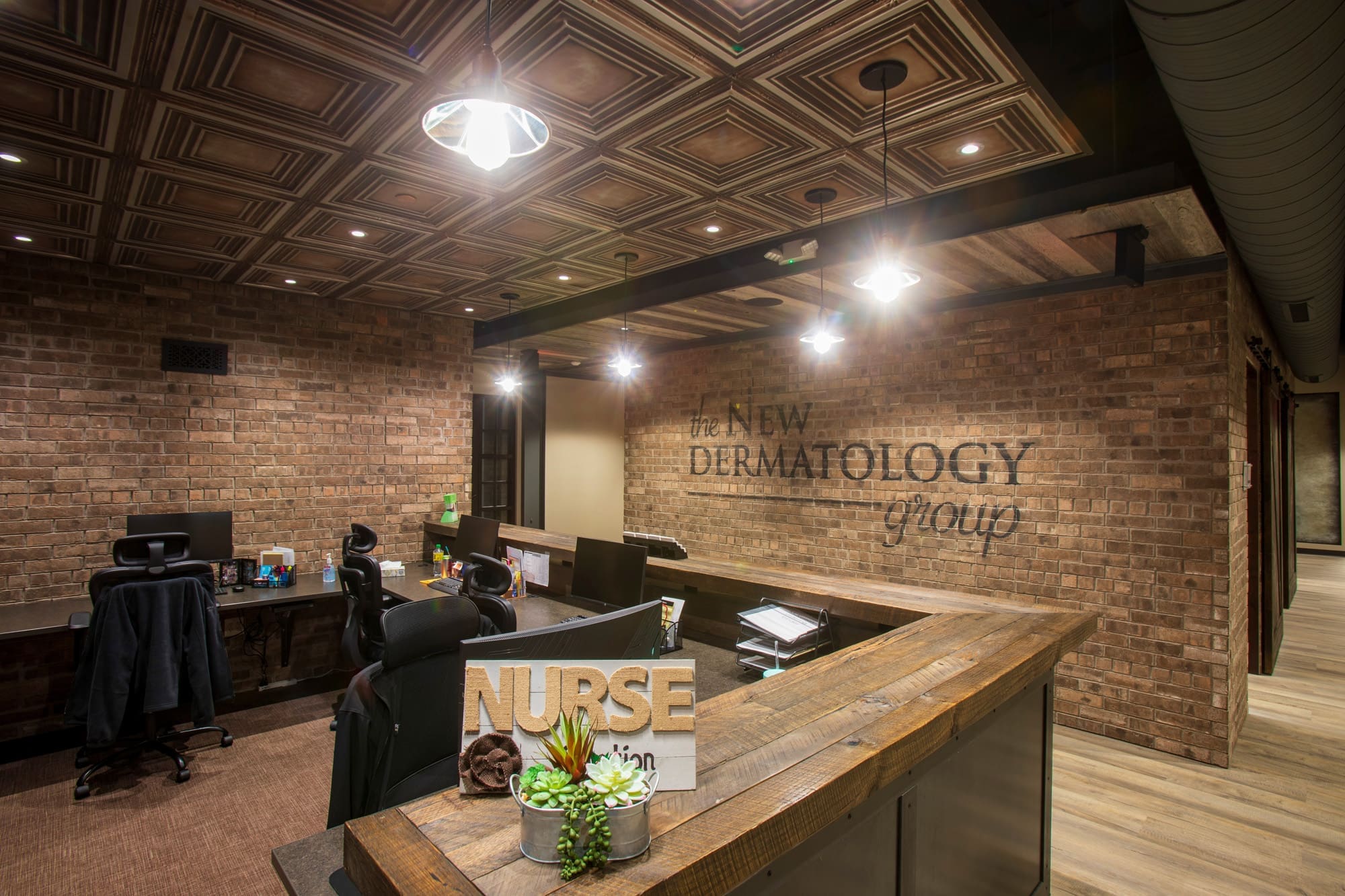 Commercial real estate reception area with brick walls, wood desk, seating, modern finishes, and visible clinic branding.