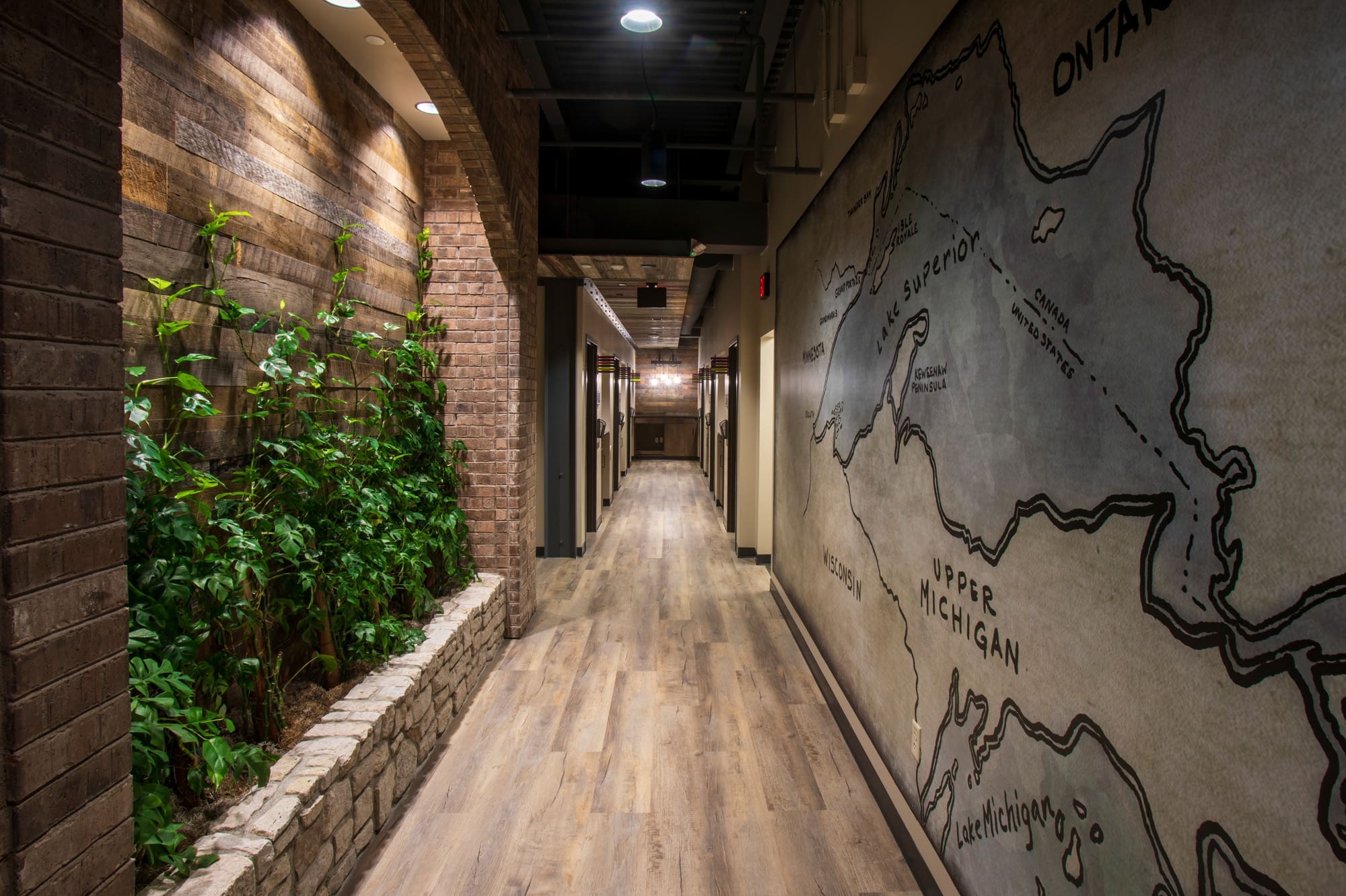 Spacious residential hallway featuring wood flooring, brick and wood-paneled walls, indoor plants, and a map mural—perfect for listings.