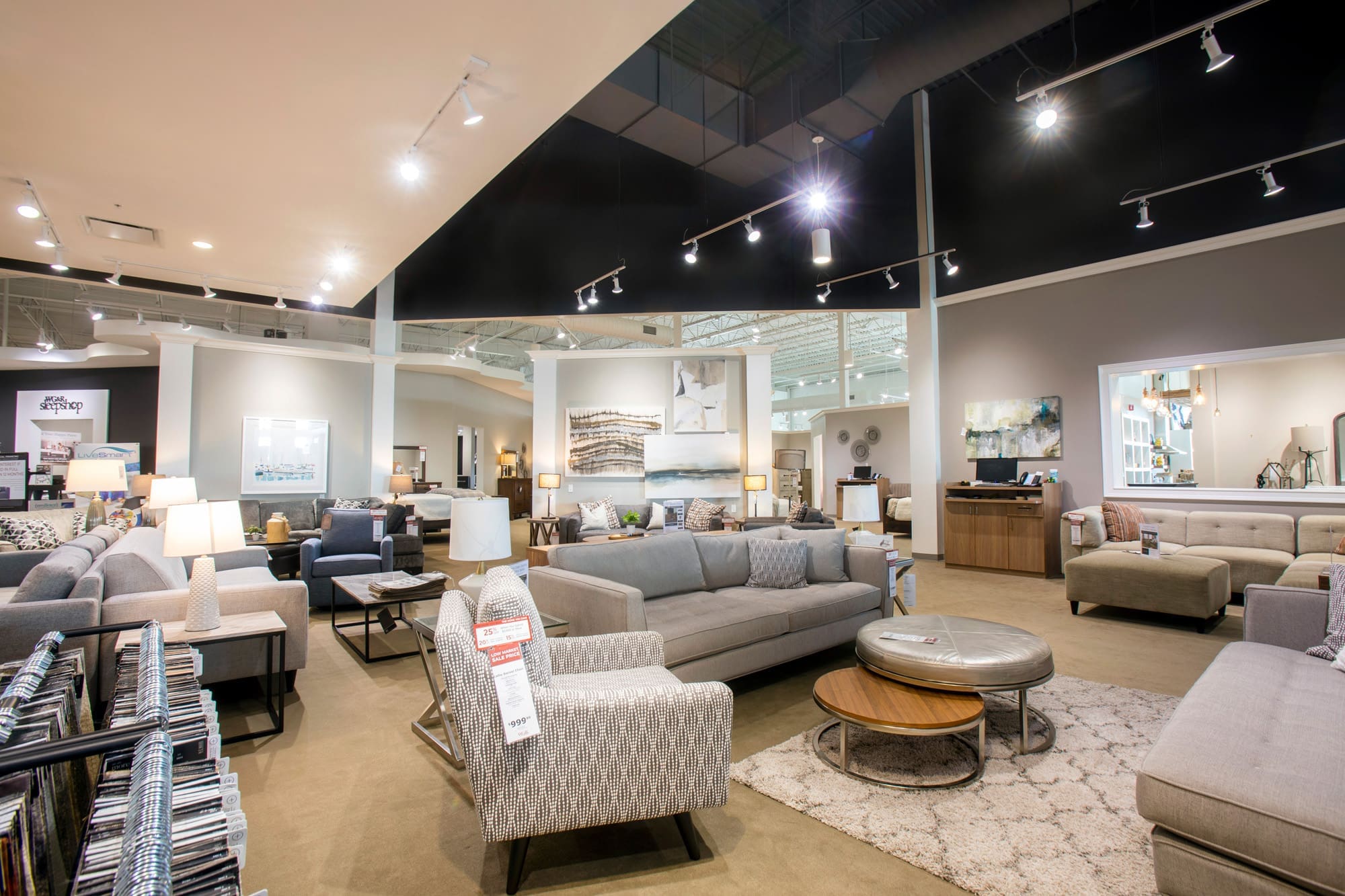 Spacious, well-lit commercial showroom highlights modern furnishings and décor on neutral carpet, ideal for real estate photography.