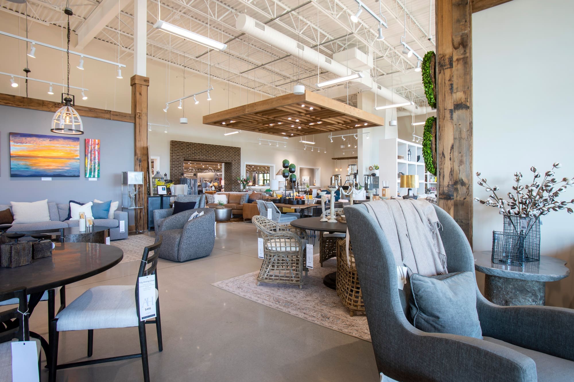 Commercial real estate showroom features modern furniture, bright lighting, high ceilings, and exposed beams for a spacious display.