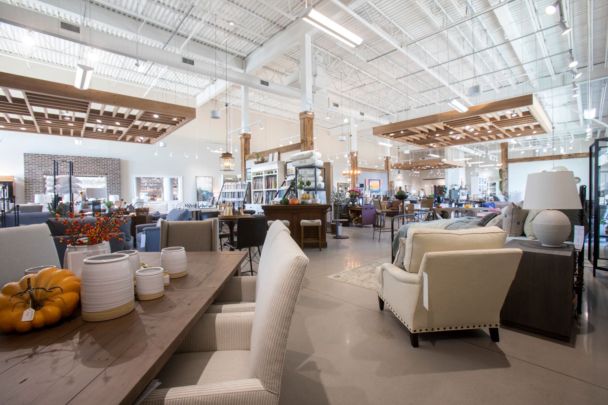 Spacious, well-lit commercial showroom with arranged sofas, chairs, tables, and decor—ideal for real estate photography or staging.